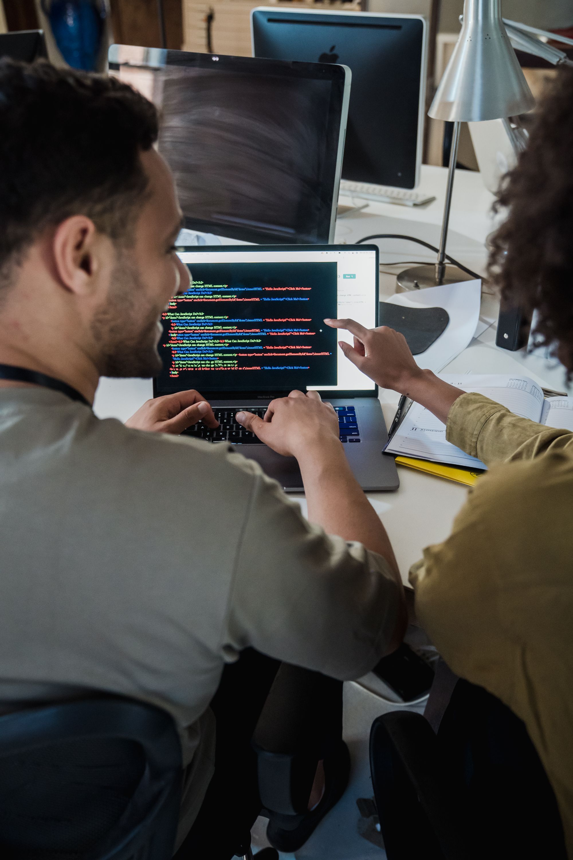 Two people working together on a laptop of source code