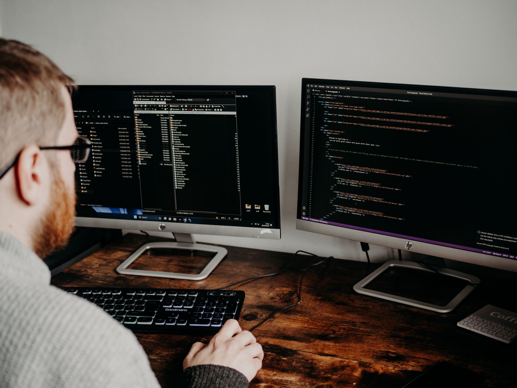A developer at a walnut desk with two monitors of source code