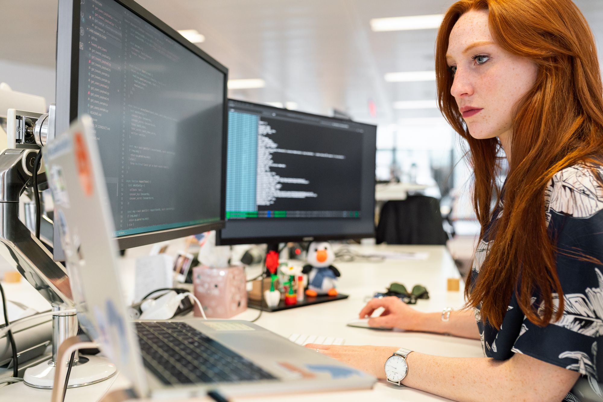 An engineer writing programmes at dual monitors in daylight